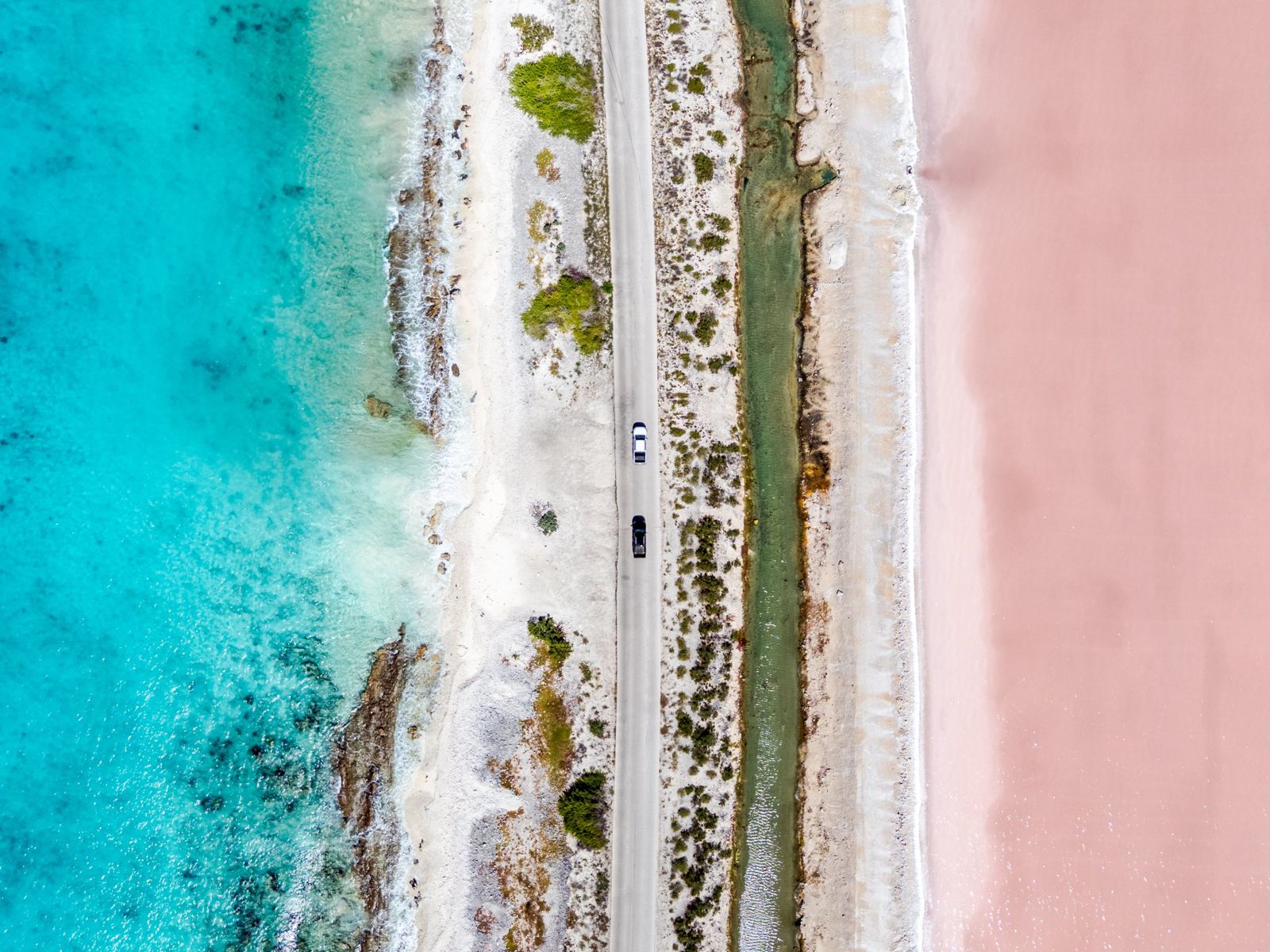Aerial view of the coastal road between the sea and the pink salt pans